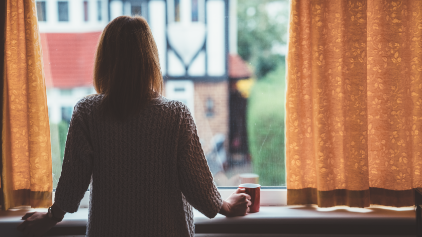 Woman drinking coffee by window dealing with anxiety during covid - Vitality