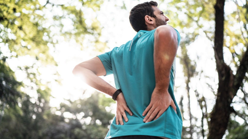 Man walking in woods easing back pain - Vitality