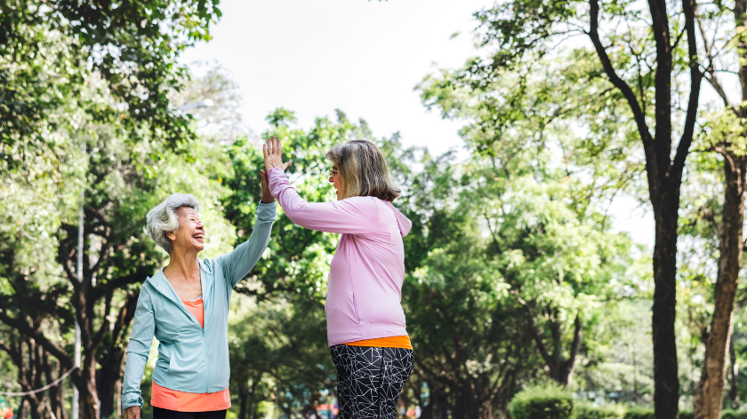 women high five outdoors doing extra activity to earn rewards - Vitality