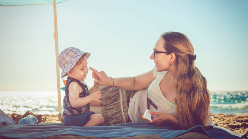 Mom and infant at the beach practicing sun safety - Vitality