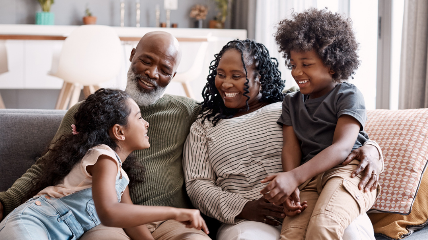 Family smiling on couch to celebrate Black History Month - Vitality