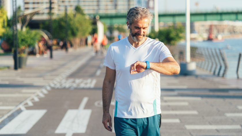 Man working out checks his fitness device outdoors - Vitality