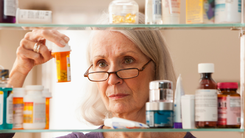 Senior woman checks prescription drug dates for safe disposal - Vitality