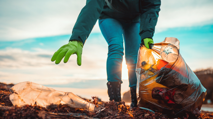 Woman picking up trash outdoors for earth day- Vitality