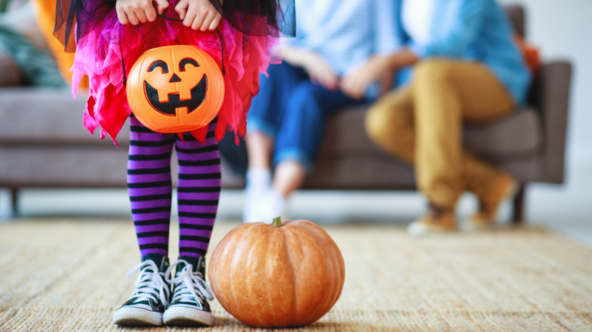 Girl with pumpkin indoors with family for a safe Halloween - Vitality