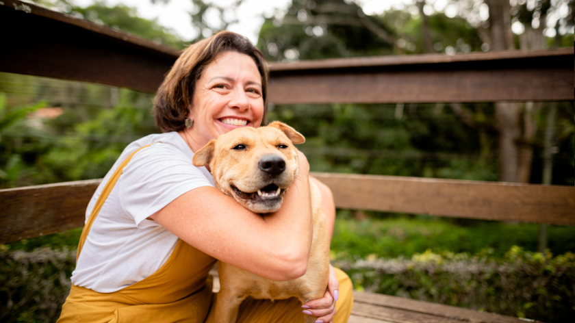 Woman hugging dog outdoors for a happier healthier future - Vitality