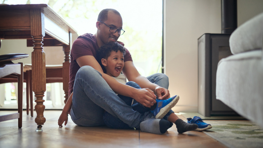 Father helping son put on shoes during daily routine - Vitality