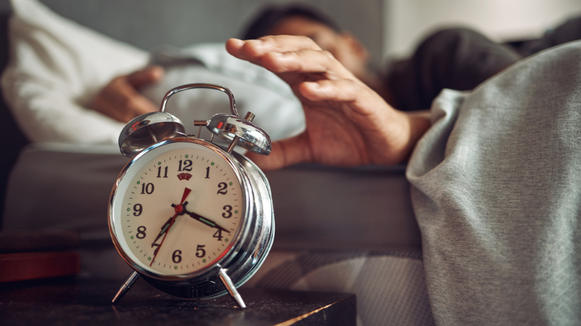 Man in bed waking up in morning with alarm clock - Vitality