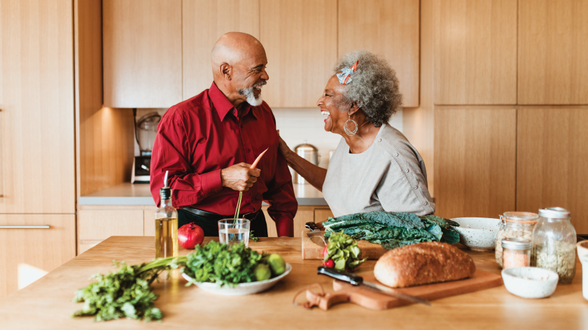 Happy couple cooking healthy food in kitchen at home - Vitality