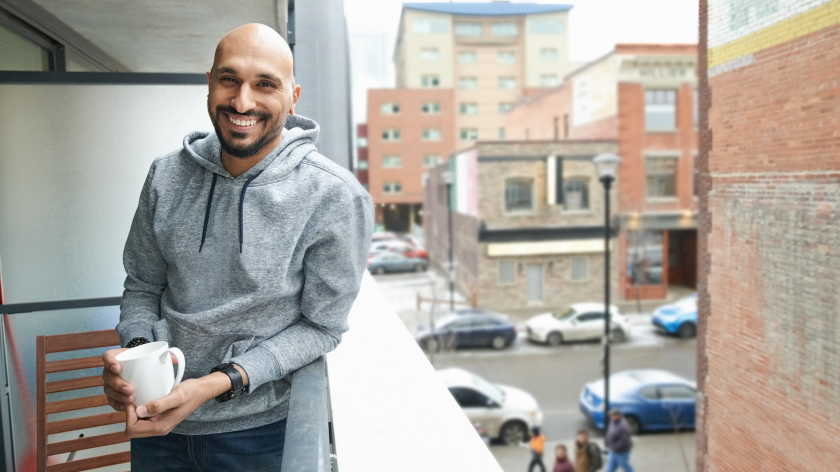 Man on balcony in city drinking coffee - Vitality