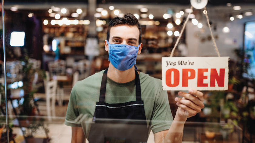 Man opens store front wearing face mask - Vitality