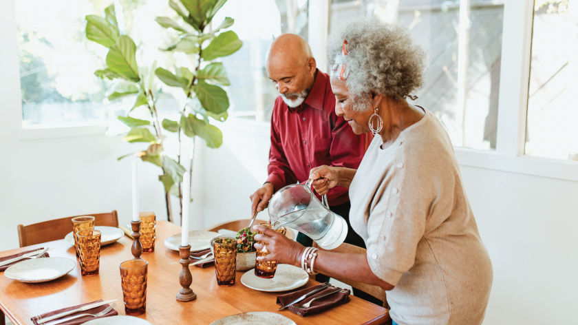 Senior couple setting table and pouring water for sober october - Vitality