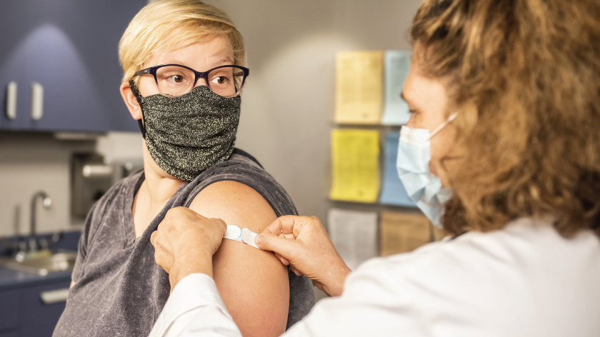 Health professional putting on bandaid after vaccine shot - Vitality