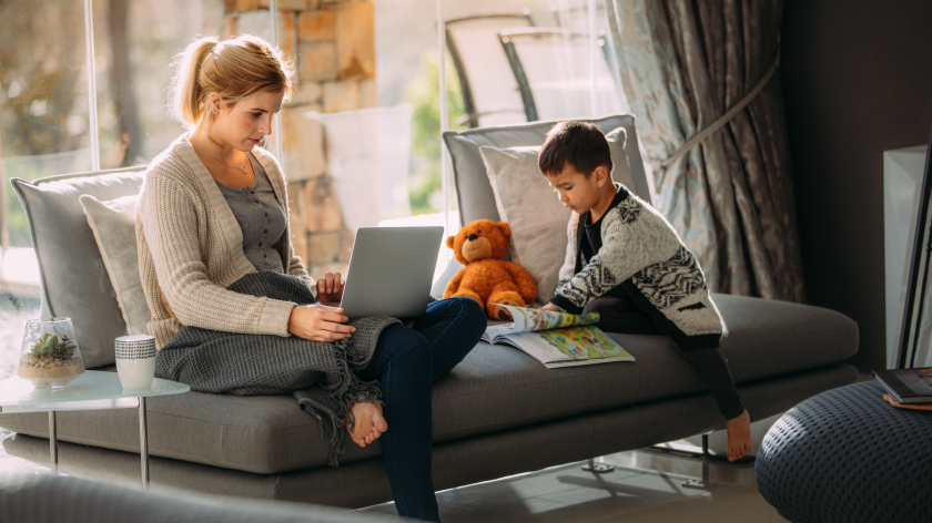 Mom working from home on laptop while son reads - Vitality