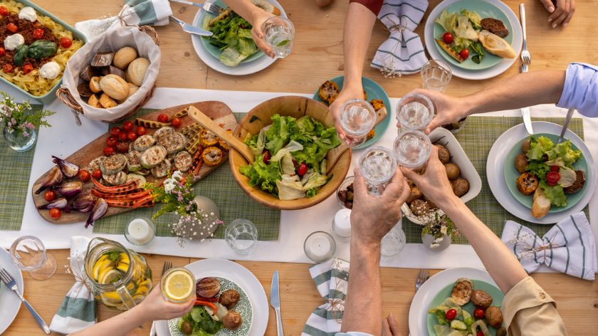 People toast water over a healthy meal served family style - Vitality