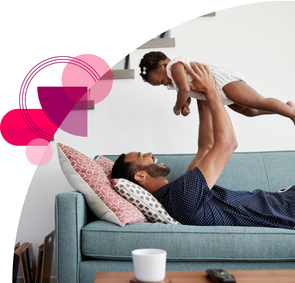 Young father holding baby in living room smiling - Vitality