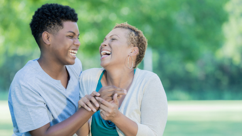 Older and younger person laughing outdoors - Vitality