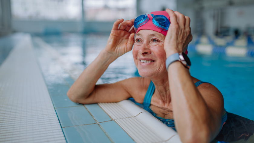 Smiling senior woman in swimming pool with goggles - Vitality