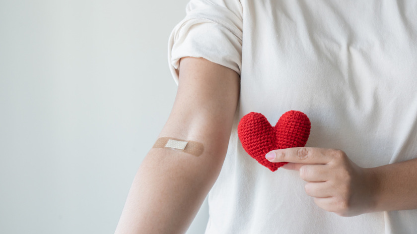 Blood donor with bandaid holding red heart - Vitality