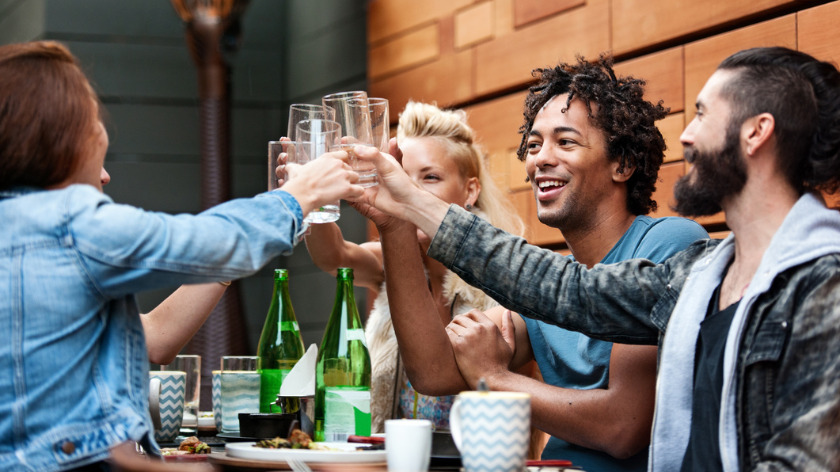 Group of friends clinking glasses at a restaurant - Vitality