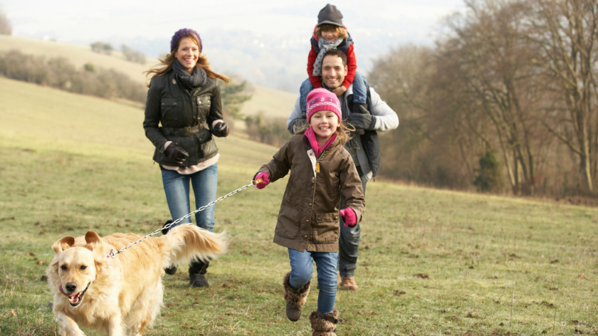 Fit family playing outdoors with dog in the fall