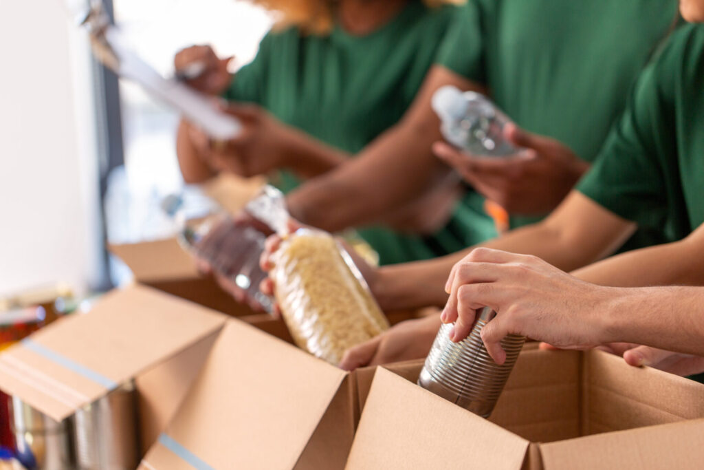 close up of volunteers packing food in boxes